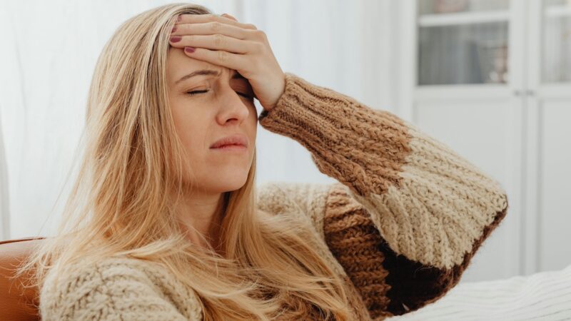 une femme qui à la main sur le front et qui à le visage qui souffre d'une migraine-neurofeedback